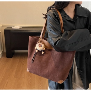 Détail du grand cabas en daim marron foncé avec passepoil et pendentif lion en peluche
