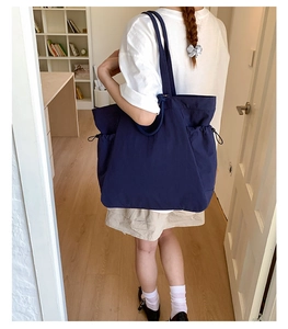 Detail view of navy blue canvas tote bag with side drawstring and spacious interior