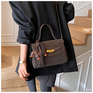Detail of coffee brown crossbody bag with gold twist lock and cute dog charm ornament
