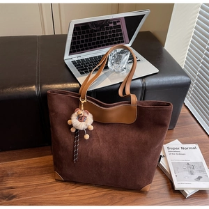 Gros plan sur un grand sac cabas en daim marron avec anses en cuir et breloque peluche