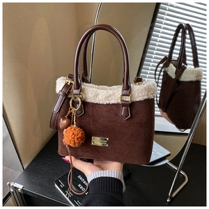 Detail of brown suede bucket bag with white faux fur trim and gold metal logo plate