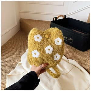 Close-up of yellow fuzzy bucket bag with white flower embroidery and soft plush texture
