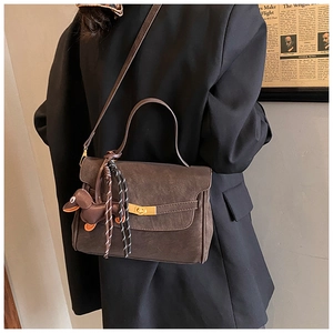 Detail of dark brown retro shoulder bag with gold twist lock and cute duck charm