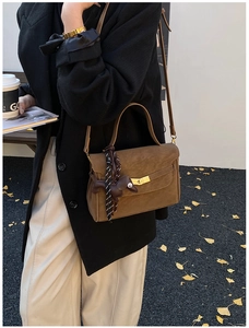Detailed close-up of brown suede handbag with gold turn-lock and leather horse charm