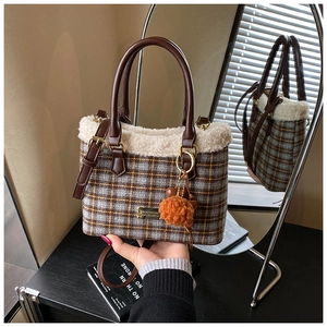 Close-up of checkered wool handbag with white faux fur trim and orange pompom detail