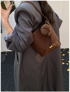Detail of dark brown suede bucket bag with a plush charm and braided drawstring