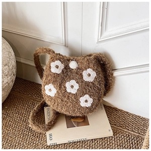 Detail shot of brown plush crochet bucket bag featuring white floral embroidery and woven strap