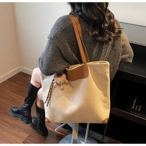 Détail du sac fourre-tout en toile avec finitions en cuir brun et pompon en peluche