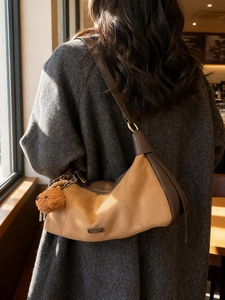 Sac bandoulière en daim marron avec breloque ours porté par un mannequin en automne