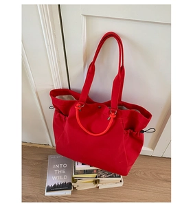 Detail view of the red canvas tote bag showing side drawstrings and multiple handles