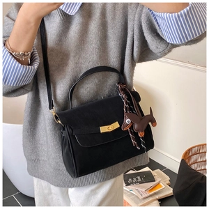 Close-up of black handbag with golden rectangular clasp and brown dachshund charm