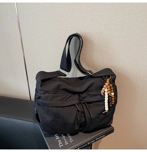 Details einer schwarzen Nylon-Umhängetasche mit Kordelzugtaschen und Perlenanhänger