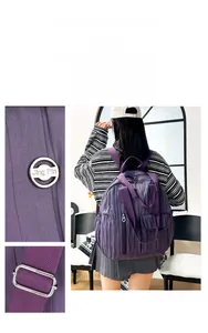 Detail of purple pleated nylon backpack featuring a metal logo and adjustable buckles
