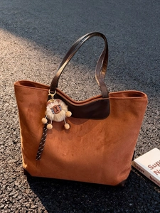 Sac cabas en daim marron avec poignées en cuir et pendentif lion sur bitume