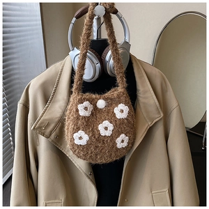 Detail of brown fuzzy bucket bag with white floral embroidery and plush puff closure
