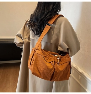 Detail der orangefarbenen Nylon-Umhängetasche mit Kordelzugverschluss und Holzperlen-Dekor