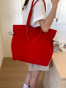 Large red canvas tote bag with drawstring detail and rope handles for daily commuting
