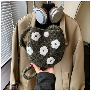 Detail of plush dark green bucket bag featuring white flower embroidery and knit texture