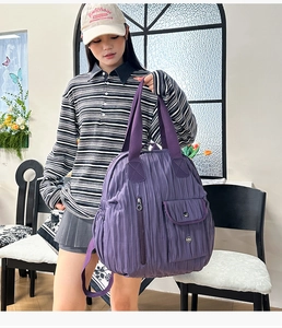 Detail of purple pleated fabric backpack showing vertical zipper and side storage pockets