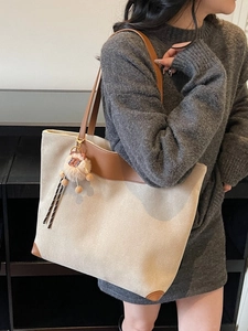 Grand sac cabas beige avec bordure en cuir marron et breloque lion en peluche sur l'épaule