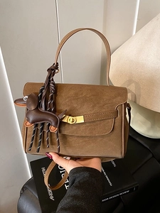 Brown faux suede shoulder bag with creative dachshund charm and metallic twist lock