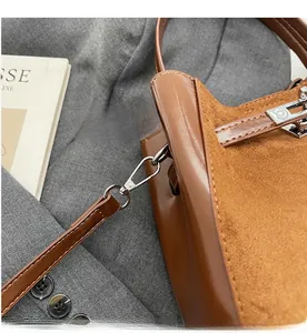 Dettaglio della borsa a secchiello marrone con mix di texture e fibbia in metallo