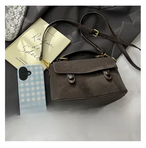 Macro view of dark brown lychee textured leather and golden hardware on the small square bag