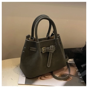 Detail of dark olive green bucket bag with contrast white stitching and decorative buckle