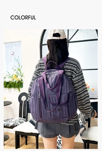 Detail of purple nylon backpack featuring stylish vertical pleats and sturdy top handle