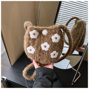 Close-up of brown plush bucket bag with white floral embroidery and button detail