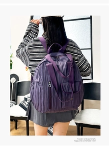 Detail of dark purple pleated backpack with functional zippers for urban travel