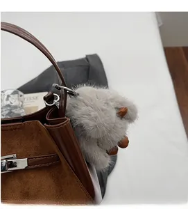 Dettaglio della borsa a secchiello in pelle opaca marrone con ciondolo a coniglio di peluche