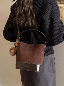 Large dark brown suede bucket bag with stylish plush pompom and leather bottom strap