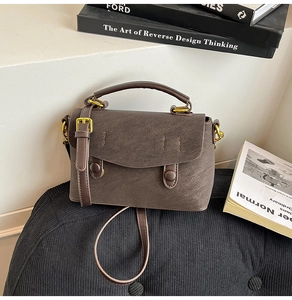 Detail of dark brown textured leather crossbody bag with vintage gold hardware