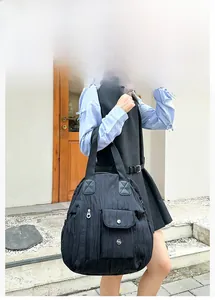 Detail showing the pleated nylon texture and multiple functional pockets of the black bag