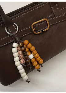 Detail eines bunten Holzperlen-Schlüsselanhängers an einer braunen Leder-Einkaufstasche