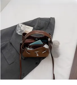 Dettaglio dell'interno della borsa a secchiello marrone con scomparti per portafoglio e trucco