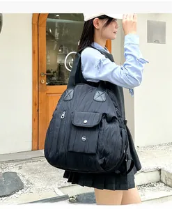 Detail of black pleated tote bag showing vertical folds and metallic buckle pocket