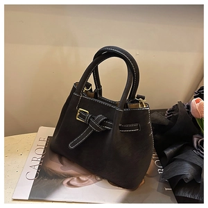 Detail of black leather handbag with gold buckle, contrast stitching and matte texture