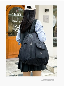 Detail of black pleated shoulder bag with side zipper pocket and metal buckle flap