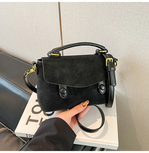 Detailed view of the matte black crossbody bag with gold hardware and top handle