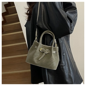 Detail of vintage dark green bucket bag with leather strap on a wooden staircase