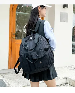 Detail of a large black backpack in wrinkled nylon featuring a flap pocket and top handle