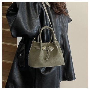 Détail du sac seau vert olive en daim avec surpiqûres contrastées porté par un mannequin