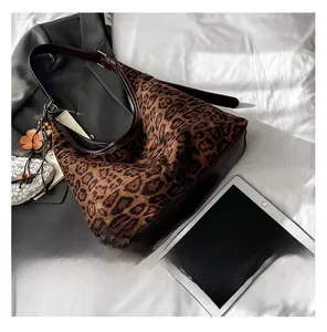Detail view of leopard print shoulder bag with brown leather strap and floral charm