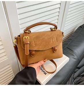 Detail of the brown crossbody bag featuring matte leather texture and gold hardware details