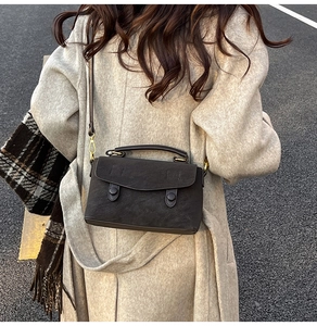 Outdoor street style view of a vintage dark brown crossbody bag on a beige coat
