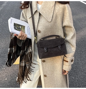 Detail of dark brown retro shoulder bag with matte leather finish and circular buckle detail