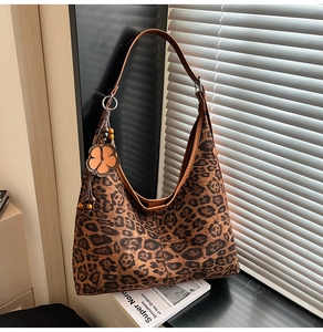 Detail of leopard print hobo bag with brown leather strap and decorative floral pendant