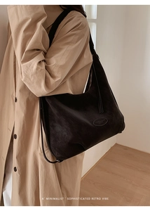 Detail einer großen schwarzen Hobo-Umhängetasche aus mattem Leder mit Reißverschluss